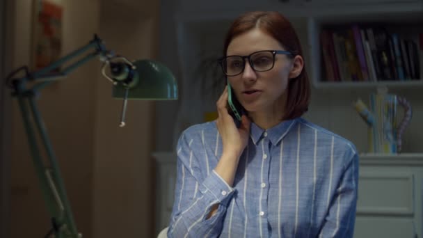 Giovani trentenni che lavorano da casa donna parlando con il cellulare. Processo educativo online. Giovane donna d'affari in occhiali parla per cella . — Video Stock