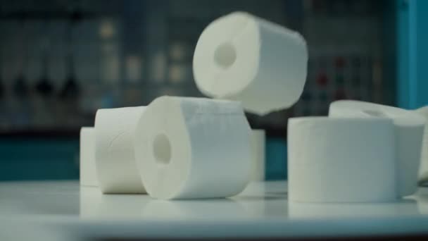 Много рулонов туалетной бумаги падает на стол на домашней кухне во время карантина коронавируса COVID-19. Забавная концепция дефицита туалетной бумаги . — стоковое видео