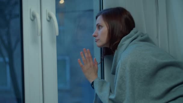 Pensive 30-tals kvinna tittar genom fönstret till kvällen tom gata. Kvinna vidrör fönsterglas sitter hemma. — Stockvideo