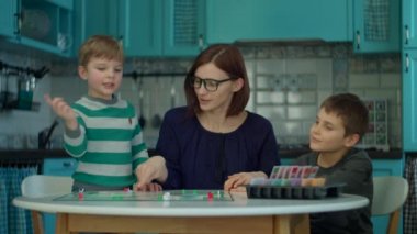 Mavi mutfakta oyun oynayan iki çocuklu 30 'lu yaşlarda bir anne. Mutlu aile evde kart oyunlarıyla eğlenir.. 