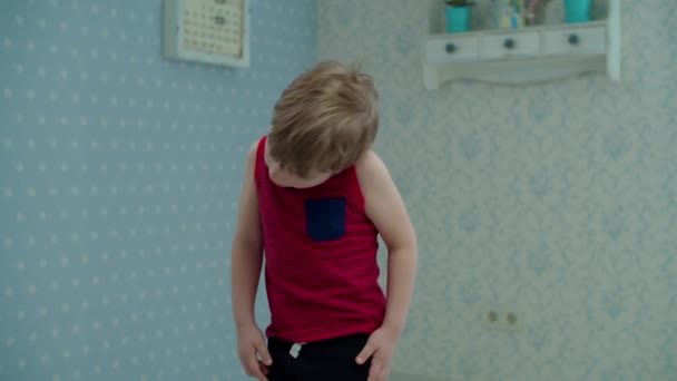 Niño preescolar haciendo complejo de ejercicios de acondicionamiento físico en casa. Niño en camiseta roja haciendo deporte en casa caliente mirando a la cámara en cámara lenta . — Vídeos de Stock