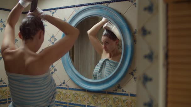 Donna trentenne in asciugamano che si tinge i capelli a casa e balla nello specchio riflesso. Bruna donna con tintura sui capelli che balla in bagno al rallentatore . — Video Stock