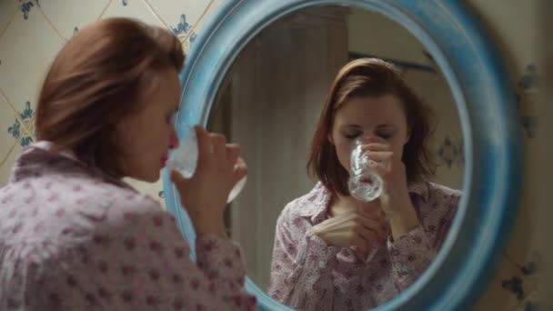 Jeune femme trentaine d'eau potable se sentant mal à la tête dans la salle de bain en face du miroir avec un mauvais maquillage et abîmé coiffure. Femme ivre d'alcool en chemise en miroir rond réflexion. Gros plan — Video