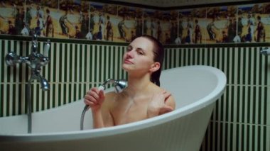 30 'lu yaşlardaki genç bir kadın evdeki yeşil banyoda kendini yıkıyor. Kadın banyo prosedürü uyguluyor. Kapat. 