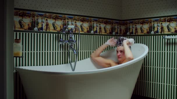 Mujer joven de 30 años lavándose el pelo en la bañera con espuma en el baño verde en casa. Mujer haciendo procedimientos de baño . — Vídeo de stock