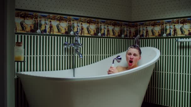 Mujer joven de 30 años cantando en el grifo en la bañera con espuma en el baño verde en casa. Mujer con champú divertido estilo de pelo haciendo procedimientos de baño . — Vídeos de Stock
