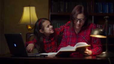 Aile bakımı anne ve kız evde ödev yaparken eğleniyor. Okullu kız ve kadın gülüyor. Ev eğitimi süreci. 