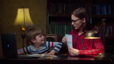 Anaokulu çocuğu, evde 30 'lu yaşların genç annesiyle matematik ödevi yapıyor. Matematiksel denklemlere bakıp not defterine yazan bir çocuk. Ev eğitimi süreci. 