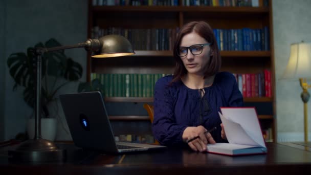 Junge Frauen in den 30er Jahren, die von zu Hause aus mit Brille auf Laptop schauen und zu Hause in Notizbuch schreiben. Online-Schulung. — Stockvideo