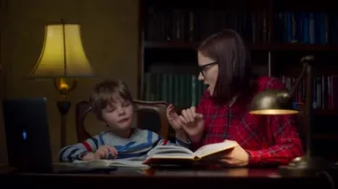 Anaokulu çocuğu evde 30 'lu yaşlardaki genç annesiyle online ödev yapıyor. Çocuk kafasını sallıyor ve anne oğluyla konuşuyor. Ev eğitimi süreci. 