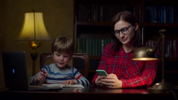 Een kleuter die huiswerk maakt met een moeder van in de dertig. Kind gooit notitieboekje terug en gelukkige familie begint te dansen. Thuisonderwijs. — Stockvideo