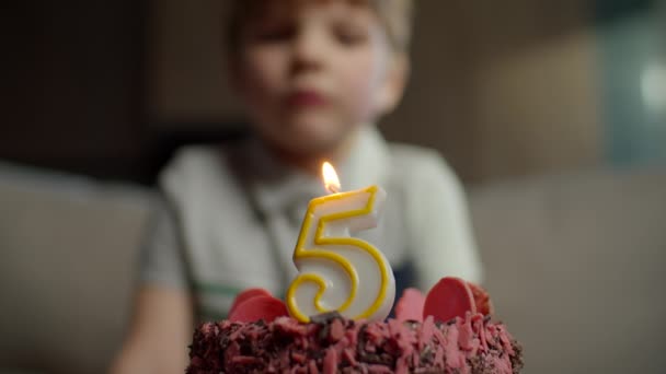 Close up of kid blowing out candle with number 5 on chocolate birthday cake in slow motion. Five years old boy celebrates birthday. — Stock Video