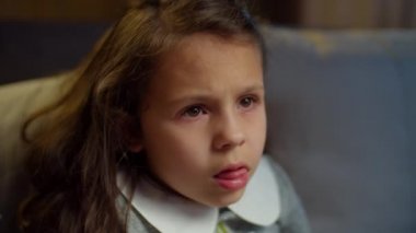 Okullu kız evdeki kanepede oturup televizyon izliyor. Evde heyecanlı bir film izleyen esmer kızın portresi. Kapat. 