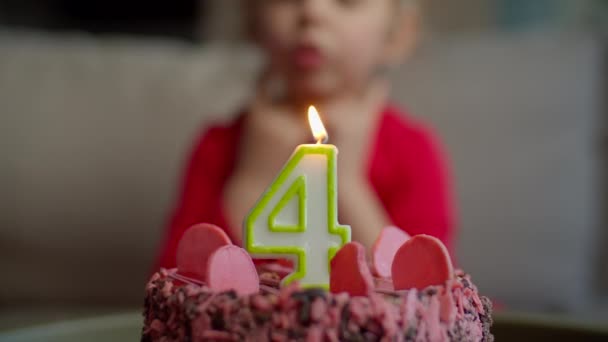 Close up of kid blowing out candle with number 4 on chocolate birthday cake in slow motion. Four years old girl celebrates birthday. — Stock Video