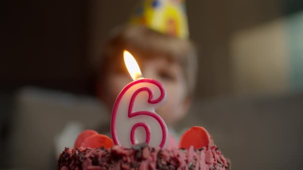 Крупним планом дитина вибухає свічкою під номером 6 на шоколадному торті в повільному русі. Шість років хлопчик святкує день народження . — стокове відео