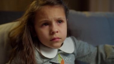 Okullu kız evdeki kanepede oturup televizyon izliyor. Evde heyecanlı bir film izleyen esmer kızın portresi. Kapat. 