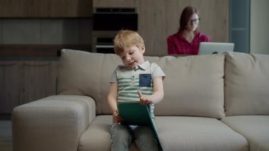 Anaokulu öğrencisi online eğitim için tablet bilgisayar kullanıyor. Annesiyle birlikte evde oturuyor. Cihazları olan bir aile evde internetten çalışıyor ve okuyor.. 