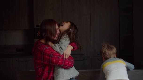 Zwei Kinder springen und tanzen mit der Mutter auf dem heimischen Sofa im dunklen Raum. Bruder und schwester having spaß mit mutter auf zuhause sofa. — Stockvideo