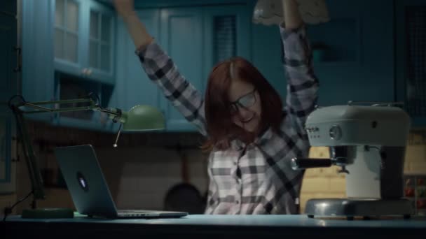 Joven mujer alegre de 30 años en gafas bailando positivo en la cocina azul tarde en la noche. La hembra está feliz de quedarse en casa. Feliz trabajo desde casa mujer . — Vídeo de stock