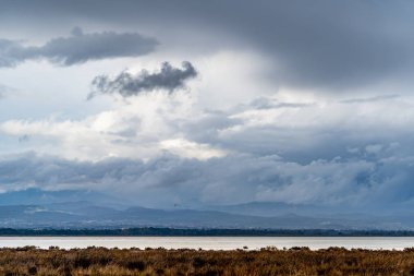 Sahilde güzel bir deniz manzarası. Arka planda muhteşem beyaz bulutlar var.