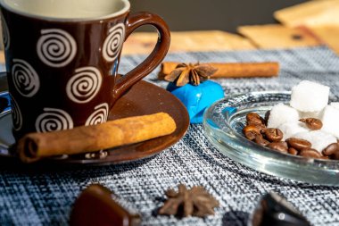 coffe cup with cinnamon and coffee beans and sugar on the table