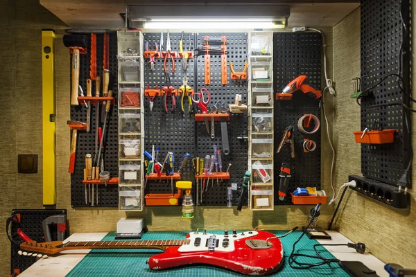 Werkbank eines Geigenbauers mit roter Gitarre — Stockfoto