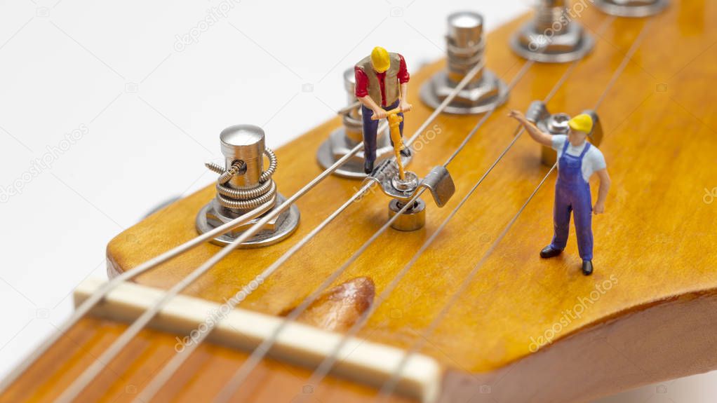 Miniature Workers Fixing The String Tree Of An Electric Guitar