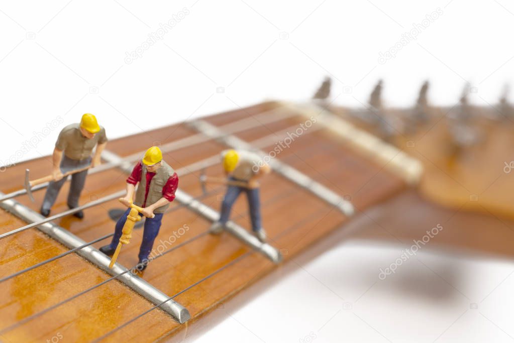 Miniature Workers Fixing The Frets Of A Guitar