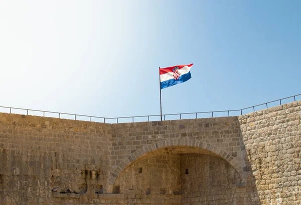 Mavi arka planda, kale duvarında gururlu ve titrek Hırvat bayrağı