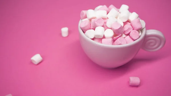 Una tazza bianca piena di gustoso marshmallow su sfondo rosa brillante — Foto Stock