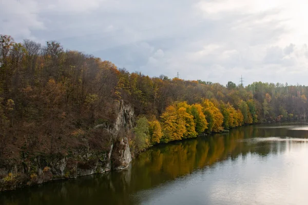 Suda yansımaları olan sonbahar ormanı olan sakin bir nehir manzarası.