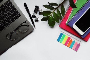 Bilgisayarlı, gözlüklü, kalemli ve akıllı telefon ekranlı bir masa. Kopyalama alanı olan üst görünüm.