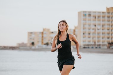 Sarışın kadın Beach siyah spor giyim ile çalışan.