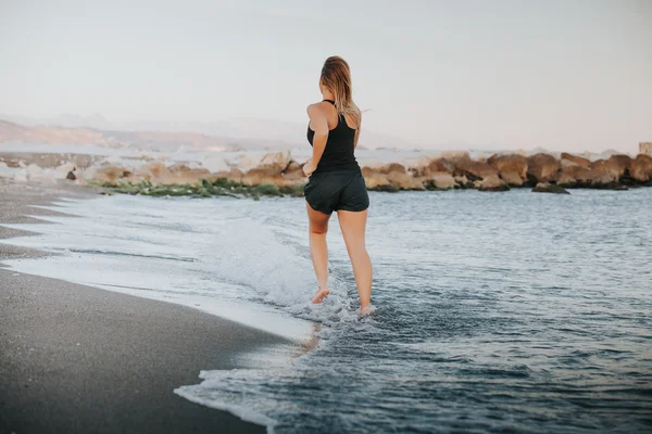 Blonde vrouw met blote voeten op het strand. — Stockfoto