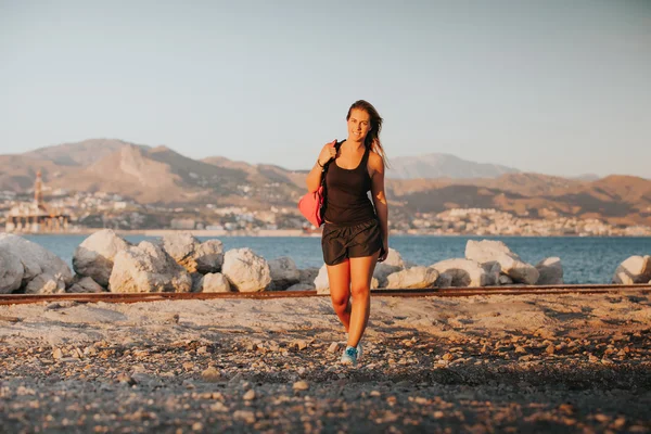 Happy woman walking with a sports bag on the shoulder. Sports co — Stock Photo, Image