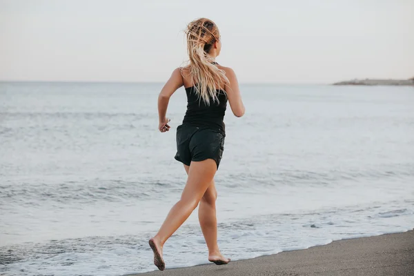 Donna bionda che corre a piedi nudi sulla spiaggia . — Foto Stock
