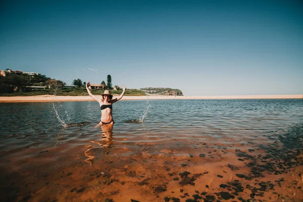 Vrouw uitspatten van water met de handen op het strand in Austral — Stockfoto