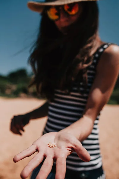 Woman holding a small shell in the hand at the coast line. — Stock Photo, Image