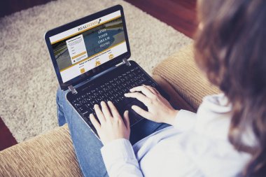 Evde otururken bir emlak web sitesi, bir ev aramak için bir dizüstü bilgisayar kullanan kadın.