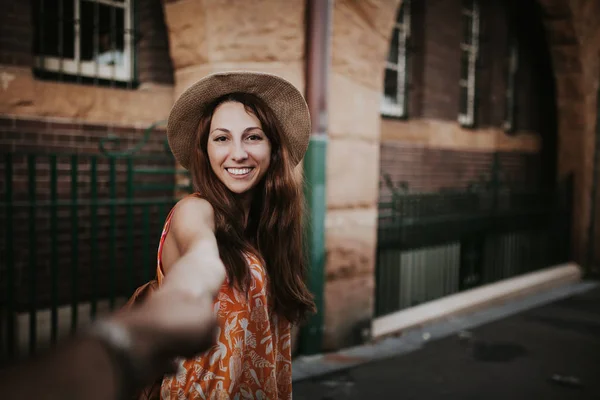 Donna che tiene per mano il fidanzato, mentre le scatta una foto . — Foto Stock