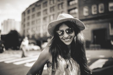 Siyah ve beyaz arka plan şehirde ile güneş gözlüklü şirin gülümseyen kız portresi.