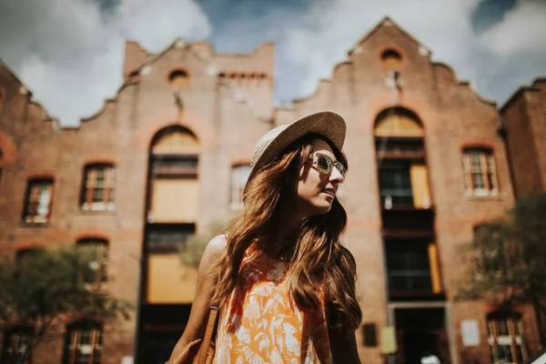 Portret van schattige lachende meisje in zonnebril met de gebouwen van de stad op de achtergrond. — Stockfoto