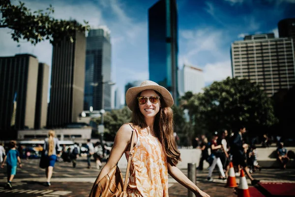 Visage souriant femme en chapeau et lunettes de soleil explorer la ville, avec Sydney skyline en arrière-plan . — Photo