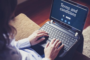 Kadın evde kanepede otururken şartlar ve koşullar bir laptop okuma.