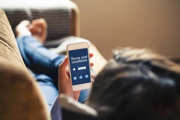 Los términos y condiciones documentan en un teléfono móvil. Mujer sosteniendo teléfono inteligente . — Foto de Stock