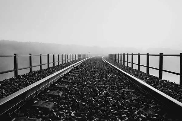 Železnice přes most do ranní mlhy. — Stock fotografie