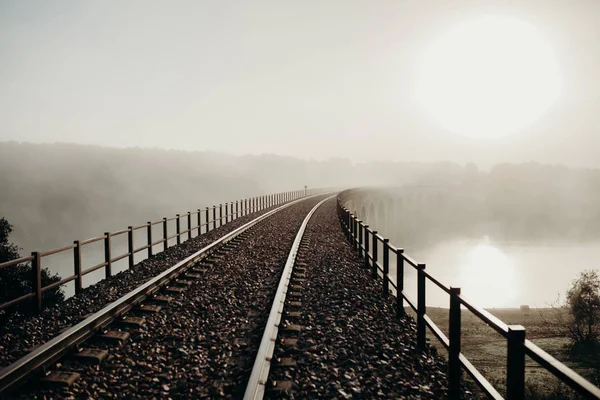 Železniční most přes řeku v mlžný den. — Stock fotografie