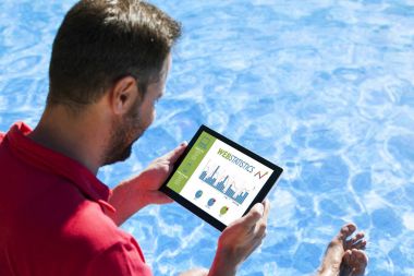 Adam Yüzme Havuzu kenarında otururken bir tablet ile web istatistik danışmanlığı.