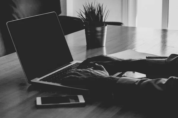 Man hands typing on a laptop in a workplace. Business black and white image.