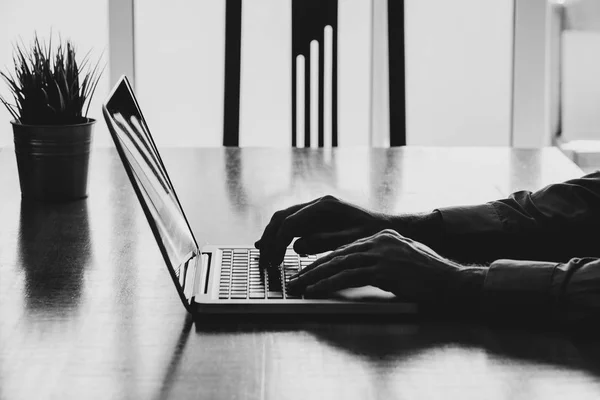 Ο άνθρωπος τα χέρια πληκτρολογώντας σε ένα φορητό υπολογιστή σε ένα χώρο εργασίας. Επιχείρηση άσπρο και μαύρο. — Φωτογραφία Αρχείου